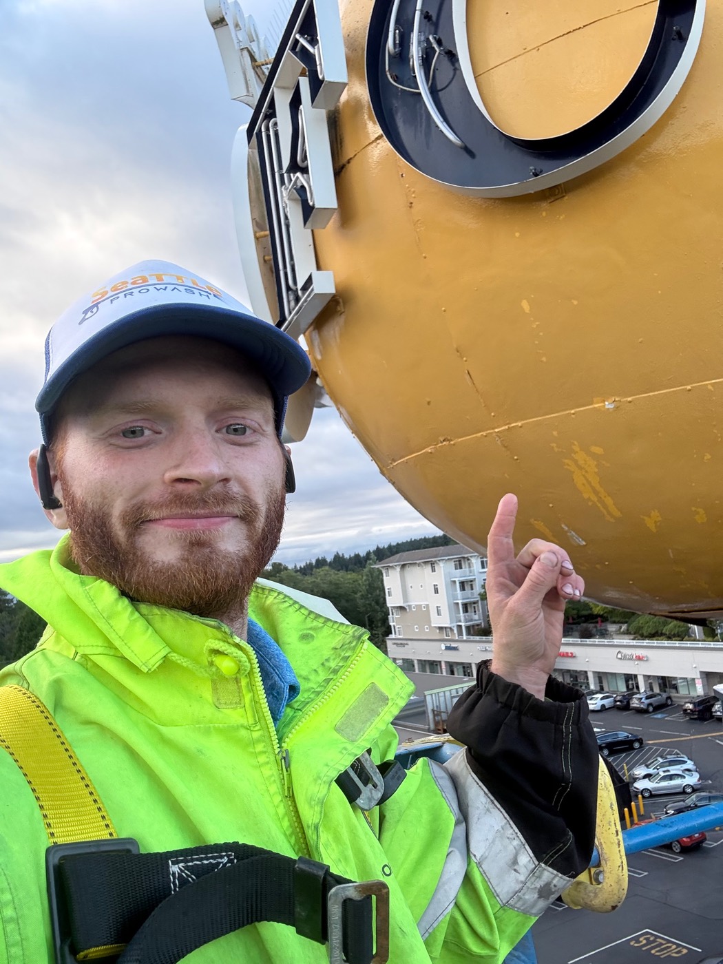 Dylan of Seattle ProWash on a boom lift 65 feet up at the QFC ball sign on Holman Road