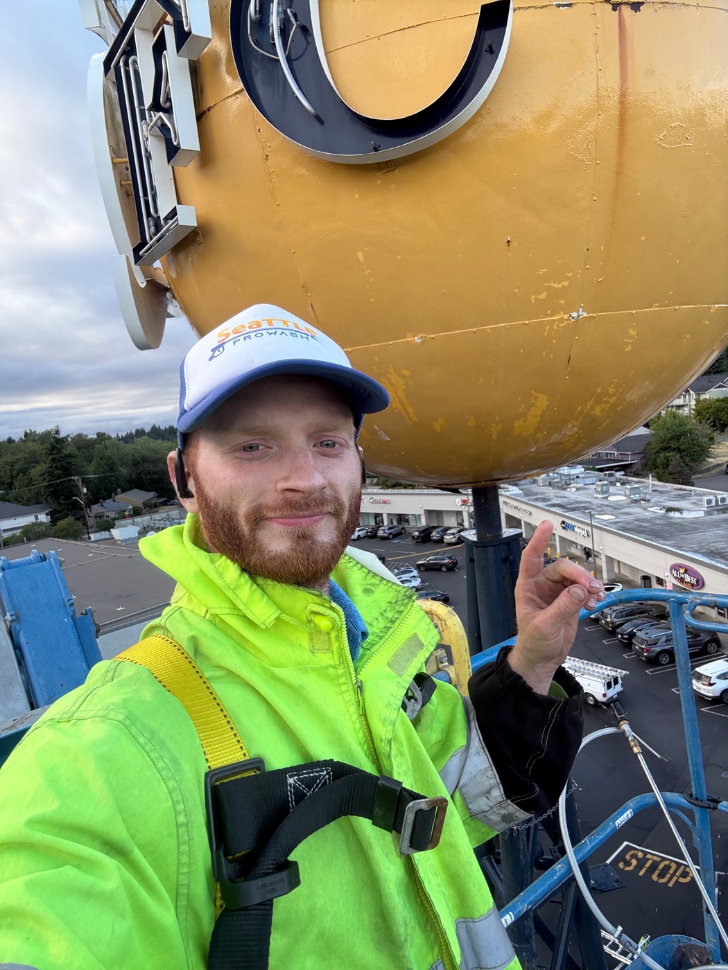 Dylan Thornsberry 65 feet up on a boom lift cleaning the landmark QFC ball sign on Holman Road, Seattle