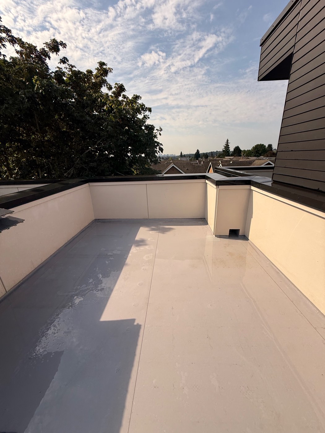 Same Seattle rooftop deck after soft washing - clean membrane and spotless white walls